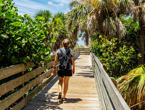 Female Tourist Walking on Wooden Boardwalk at Venice Beach, Venice, Florida, USA - Powered by Adobe