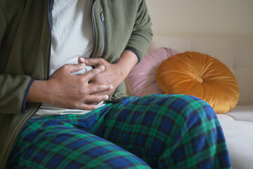 Man experiencing stomach pain while sitting on a couch