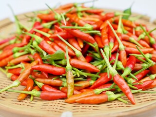 Fresh red bird's eye chilis are placed in a bamboo basket.