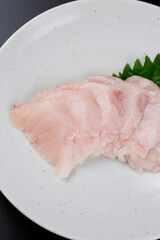 皿に盛られたサワラのお刺身 黒背景