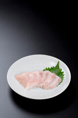 皿に盛られたサワラのお刺身 黒背景