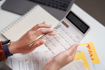 Tax calculation. A woman using a calculator to manage tax finances.