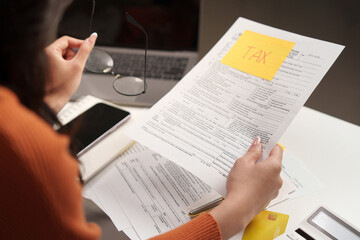 Tax review. A woman examining tax documents with glasses.