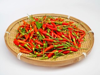 Fresh red bird's eye chilis are placed in a bamboo basket.