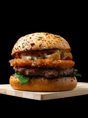 Gourmet Beef Burger with Crispy Hash Brown Patty, Melted Cheese, Spinach, and Caramelized Onions on an Herb Bun, Isolated on Black Background