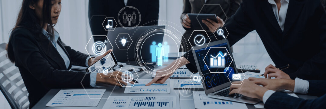 A diverse business team collaborates in a modern office, utilizing technology and data visualization tools to discuss strategy and drive productivity in their projects. Trope - Powered by Adobe