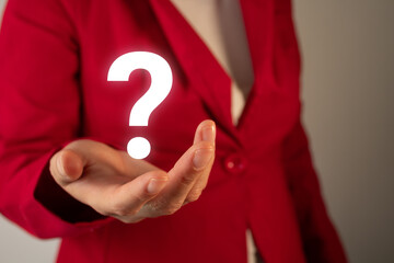 Close-up of a businesswoman's hand in a red blazer, holding a question mark