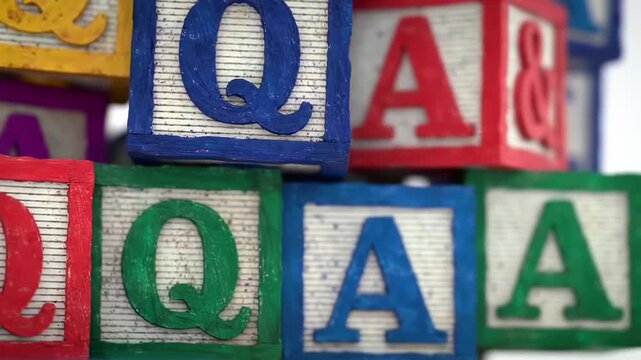 Colorful wooden blocks with letters stacked, close up with letters Q and A visible