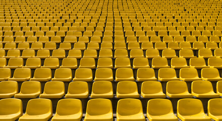 Fototapeta premium yellow tribunes. seats of tribune on sport stadium. empty outdoor arena. concept of fans. chairs for audience. cultural environment concept. color and symmetry. empty seats. modern stadium