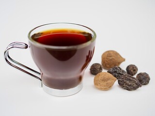 Triphala water is in a glass placed on a white background.