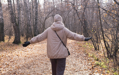 Happy, smiling 40-year-old woman enjoys the warm, sunny weather in an autumn park. Hello, autumn!