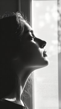 Monochromatic portrait captures woman in contemplative mood by window light