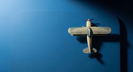 Fototapeta premium A Vintage Biplane Toy Suspended Against a Deep Blue Background