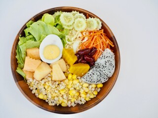 Vegetable and fruit salad placed in wooden bowl on a white background. Healthy food.