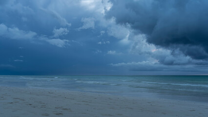 Seascape before the rain. Low dark clouds hang over the ocean. Waves are foaming on a sandy beach....