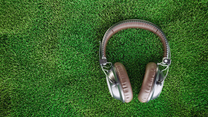 Retro brown headphone on green grass background top view