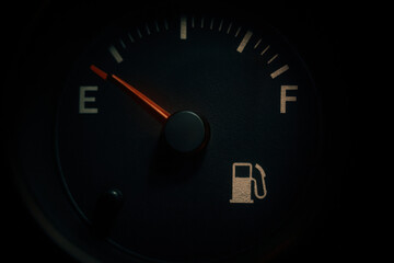 Fuel gauge showing low level, indicating need for refueling. needle points towards empty, emphasizing urgency and caution