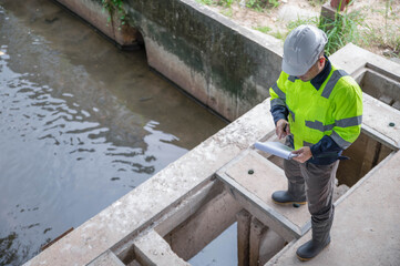 An expert inspector is inspecting the water passing through a river waste scoop to detect any abnormalities in the operation of the scoop.