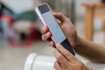 Woman's hand holding a smartphone. Reading books on smartphone.