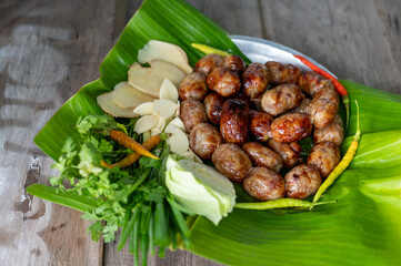 Delicious Thai Grilled Sausages with Fresh Herbs and Spices on a Green Banana Leaf Plate