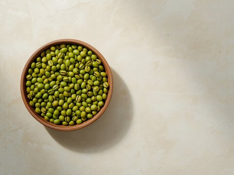 Mung beans in a terracotta bowl on textured stone; natural overhead still life perfect for recipes, Asian pantry, sprouting, nutrition, and wholesome cooking.