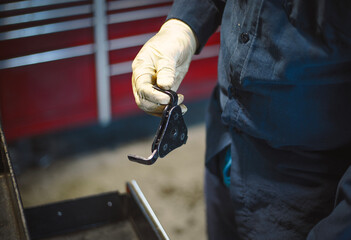 Close-up of a worker's hand with a car repair tool in a car repair shop