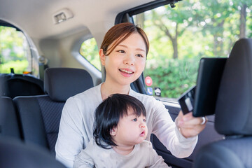 赤ちゃんを抱いてタクシーに乗る若いお母さん © maroke