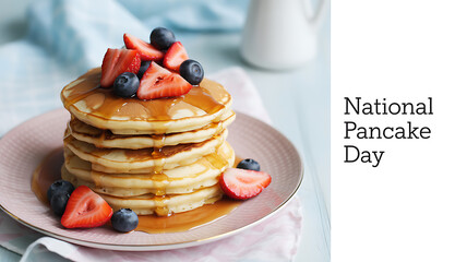 Stack of pancakes topped with strawberries, blueberries, and syrup on a plate for National Pancake Day
