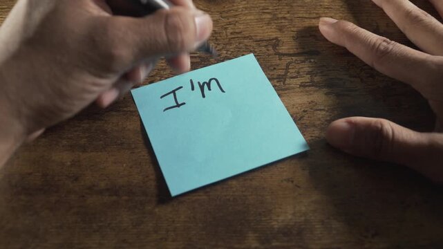 Person writing a positive message on a sticky note