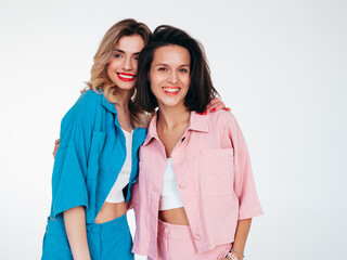 Two young beautiful smiling female in trendy summer clothes. Carefree women posing in studio....