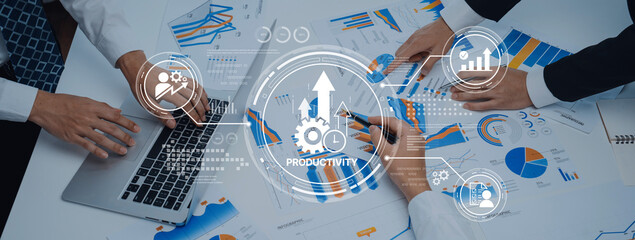 Team evaluates productivity through financial data analysis with various charts and graphs on the table, utilizing technology for effective decision-making. Trope