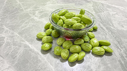 Fresh Green Stink Beans Petai Parkia Speciosa in Glass Bowl on Marble Background – Tropical Asian Ingredient and Exotic Organic Food Concept