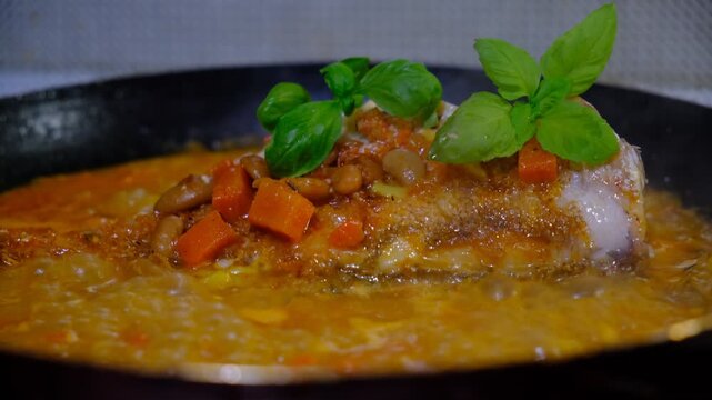 Red sea perch fish with vegetables stew on cooking pan. Cooked with vegetables in samfaina, with tangy tomato caper sauce in a pan. Traditional recipe of Mediterranean gastronomy.