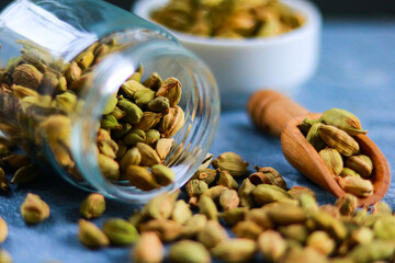 Cardamom in a glass jar on a blue background. Selective focus