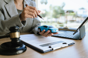 A lawyer signing a car contract with a gavel and a toy car on the desk, symbolizing car law, insurance, or legal agreement.