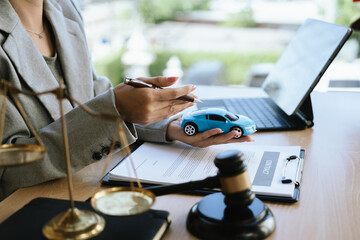 A lawyer signing a car contract with a gavel and a toy car on the desk, symbolizing car law, insurance, or legal agreement.