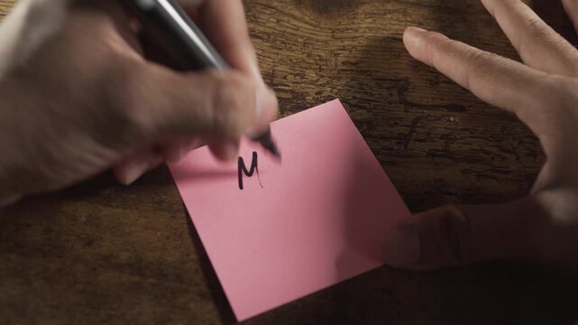 Human hands writing romantic miss you message on pink note