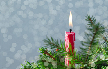 Burning red candle in candlestick on fir tree branch close up, . christmas tree with candle. ritual for holiday. Copy space