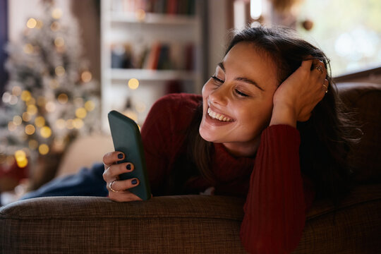 Happy woman reading text message on cell phone on Christmas day at home.