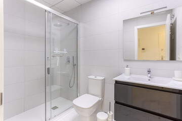 Modern bathroom with walk-in glass shower, toilet, and glossy vanity with mirror