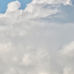 Obraz premium A detailed, closeup view of dense, towering cumulonimbus clouds, showing various shades of white and grey, suggesting heavy weather and dramatic atmospheric depth.