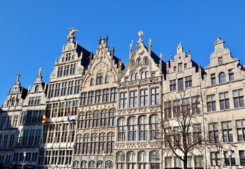 Guildhalls on Grote Markt in Antwerp, Belgium, featuring traditional step gables and golden statues under a clear blue sky.