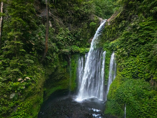 Naklejka premium Aerial view of the magnificent Tiu Kelep waterfall surrounded by dense jungle at Mount Rinjani, Lombok, Indonesia — breathtaking tropical nature