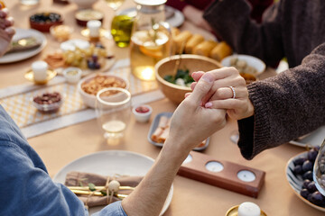 Caucasian middle aged woman and man holding hands across table during meal, hands clasped in gesture of affection, surrounded by food and drinks