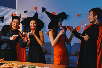 Joyful office Halloween party with coworkers in costumes, celebrating with drinks and laughter,...