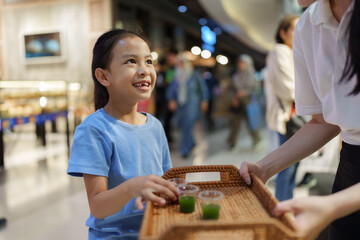 Happy girl receiving healthy drink samples in mall