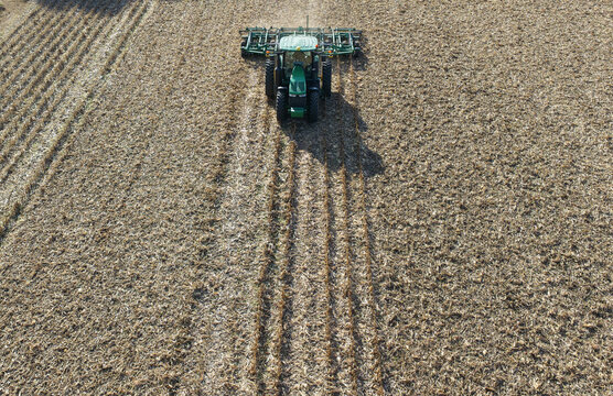 Aerial view of tractor plowing soil. Tractor plowing farmland. Agricultural work. Tractor cultivating soil. Farming machinery. Tractor plowing land. Farm machinery working. Plowing from top.