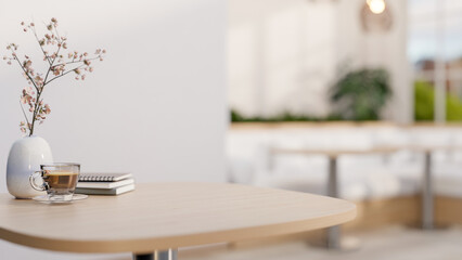 Coffee in glass cup and books aside flower vase on wooden stool table in a cosy cafe or coffee shop