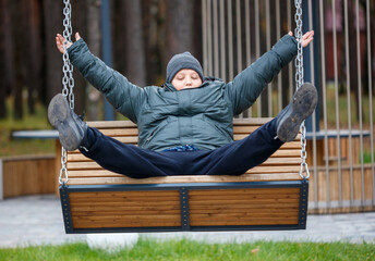 A boy is sitting on a wooden swing