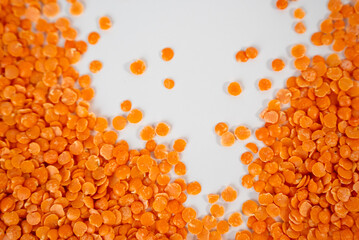 Orange lentils scattered on white surface, high protein vegan ingredient ideal for clean eating and healthy lifestyle concepts. 